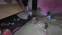 Anak-anak berdiri di kamar yang banjir di rumah mereka setelah hujan lebat di Karachi, Pakistan, Minggu, (26/7/2020). Tingginya banjir membuat air masuk ke rumah warga. (AP Photo/Fareed Khan)