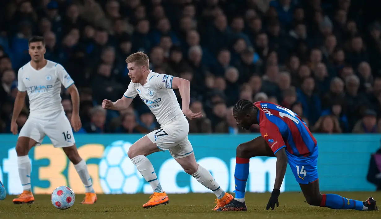 Gelandang Manchester City, Kevin De Bruyne membawa bola usah melewati pemain Crystal Palace, Jean-Philippe Mateta dalam pertandingan lanjutan Liga Inggris di Selhurst Park, London, Selasa (15/3/2022). Manchester City bermain imbang atas Crystal Palace 0-0. (AP Photo/Matt Dunham)