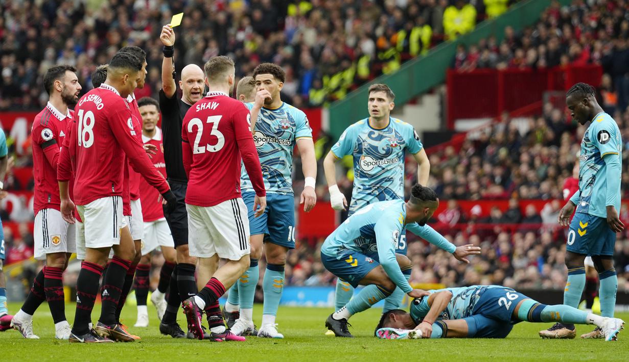 Wasit Anthony Taylor memberikan kartu kuning kepada pemain Manchester United, Casemiro, setelah melakukan pelanggaran kepada pemain Southampton, Carlos Alcaraz pada laga Liga Inggris di Stadion Old Trafford, Minggu (12/3/2023). (AP Photo/Jon Super)