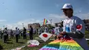 Seorang anak Palestina membawa layangan warna-warni dan bendera Jepang dalam aksi solidaritas peringatan tujuh tahun gempa dan tsunami Jepang di Gaza, Selasa (13/3). (SAID KHATIB/AFP)