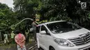 Sebuah mobil tertimpah lampu jalanan di kawasan jalan purworejo Menteng, Jakarta, Senin (27/11). Akibat hujan deras dan angin kencang sebuah pohon tumbang dan lampu jalan mengenai mobil Alphard putih yang terparkir. (Liputan6.com/Faizal Fanani)