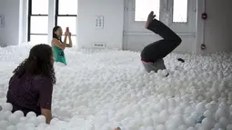 Para karyawan dan masyarakat umum saat bermain dan bersantai di kolam bola yang ada di kantor SoHo, New York City, Selasa (25/8/2015). Ada sekitar 81.000 bola putih disebar diruangan ini. (REUTERS/Mike Segar)
