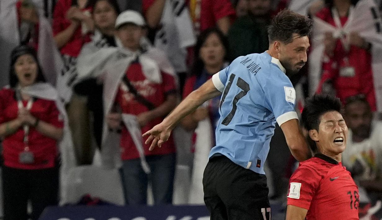Pemain Uruguay, Matias Vina (kiri) mendorong pemain Korea Selatan Lee Kang-in saat berebut bola diudara. (AP Photo/Martin Meissner)