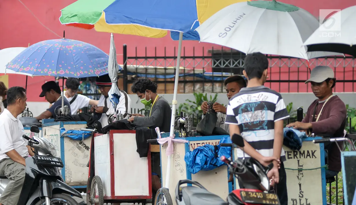Sejumlah penjahit keliling saat menerima orderan pelanggan, Jakarta, Kamis (22/6). Para penjahit yang biasanya berkeliling masuk kampung ini lebih memilih untuk mangkal di saat jelang lebaran. (Liputan6.com/Yoppy Renato)