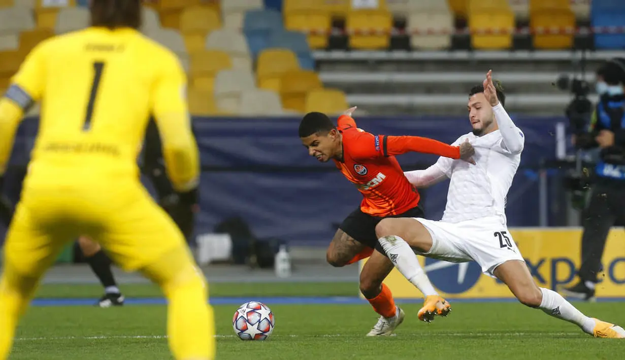 Pemain Borussia Moenchengladbach, Ramy Bensebaini, berebut bola dengan pemain Shakhtar Donetsk, Dodo, pada laga Liga Champions di Stadion Olimpiyskiy, Selasa (3/11/2020). Moenchengladbach menang dengan skor 6-0. (AP/Efrem Lukatsky)