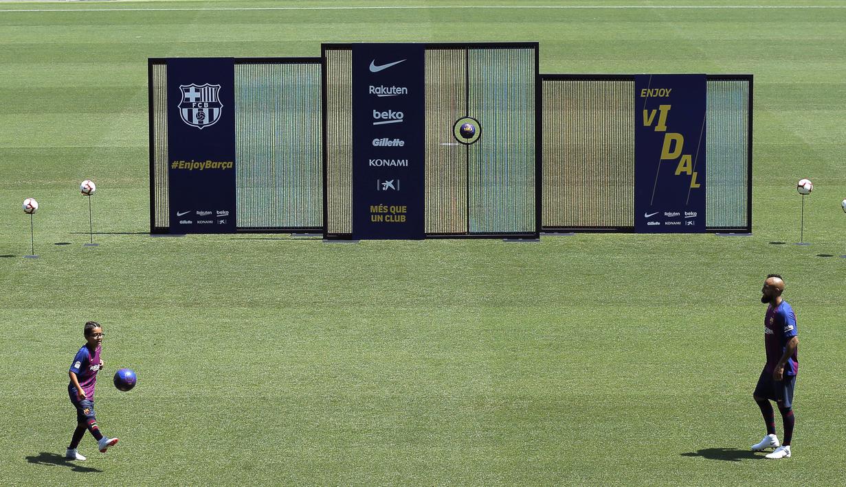 Pemain baru Barcelona, Arturo Vidal, bersama anaknya Alonso, saat perkenalan di Stadion Camp Nou, Senin, (7/8/2018). Barcelona merogoh kocek sebesar 19 juta euro untuk mengamankan jasa pria berkebangsaan Cile itu. (AP/Manu Fernandez)