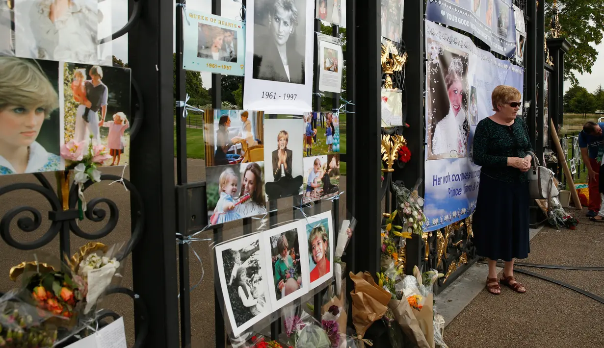 Seorang wanita berpose dekat memorabilia Putri Diana di luar Istana Kensington, London, Selasa (29/8). Pernak-pernik serta bunga didedikasikan khusus untuk sang putri yang meninggal akibat kecelakaan mobil pada 31 Agustus 1997 (AP Photo/Alastair Grant)