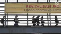 Pejalan kaki melintas di JPO Jalan Sudirman yang dipasangkan Spanduk peringatan revitalisasi, Jakarta (6/11). Tiga JPO yang akan direvitalisasi JPO Bundaran Senayan, JPO Polda Metro Jaya, dan JPO di Stadion Utama GBK. (Liputan6.com/Immanuel Antonius)