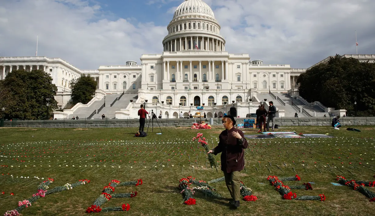 Seorang wanita meletakkan bunga di halaman rumput Gedung Capitol (kantor kongres) Amerika Serikat, Senin (19/3). 5000 bunga diletakkan untuk mengenang ribuan anak yang tewas akibat pengeboman oleh koalisi pimpinan Arab Saudi di Yaman (AP/Jacquelyn Martin)