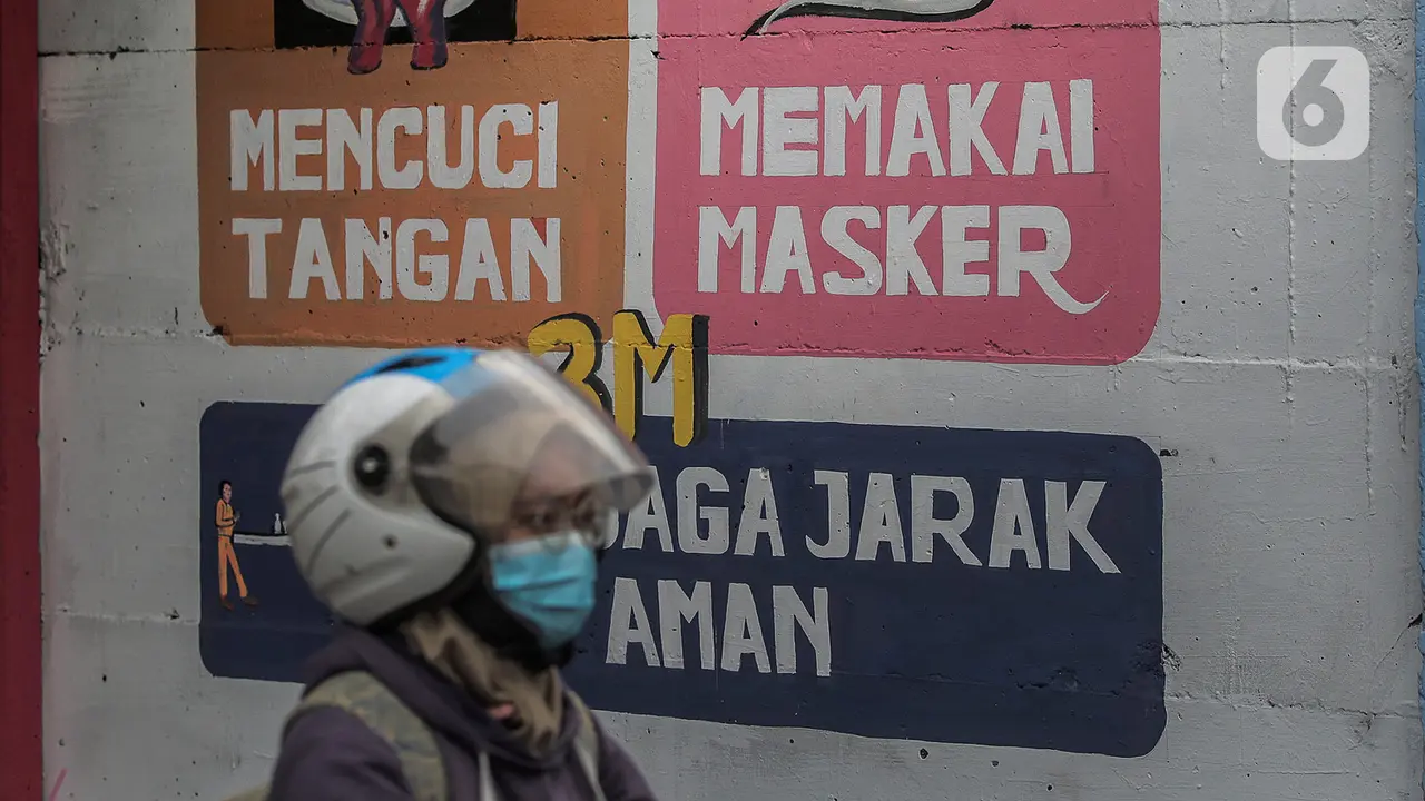 Pengendara motor melintasi mural bertuliskan protokol kesehatan COVID-19 di Kawasan Kota Bambu, Jakarta, Selasa (20/10/2020).