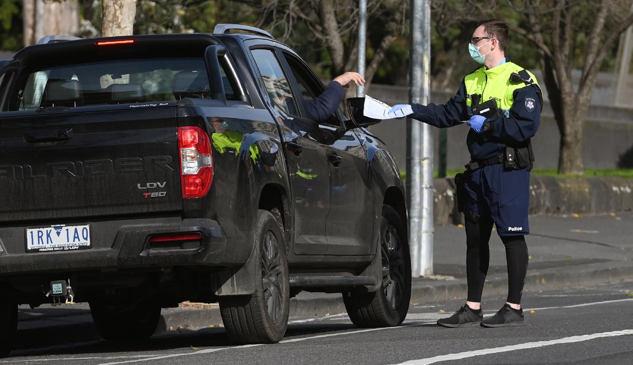 Petugas polisi menghentikan mobil untuk pemeriksaan izin selama tahap empat penguncian kota yang ketat karena wabah COVID-19 di Melbourne (11/8/2020). Negara bagian Victoria melaporkan 19 kematian akibat virus corona pada 11 Agustus. (AFP/William West)