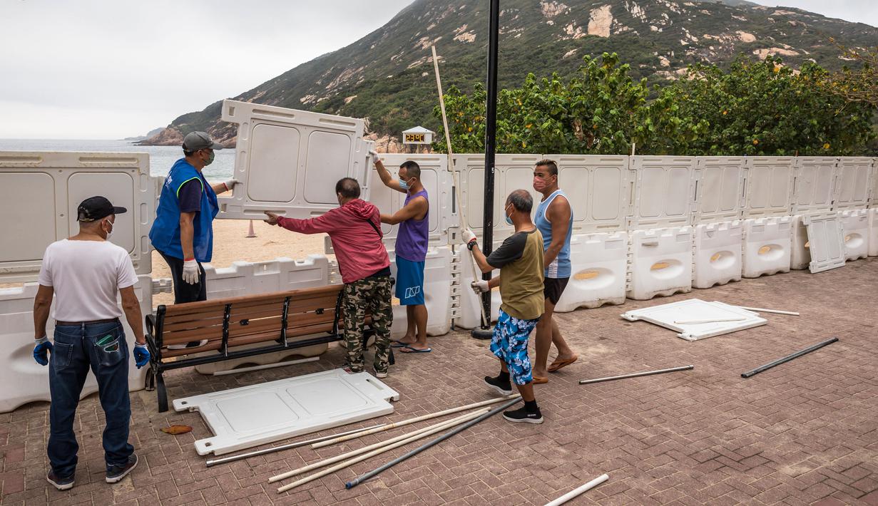 Pekerja memasang pagar untuk memblokir akses ke Pantai Shek O di Hong Kong, Kamis (17/3/2022). Pemerintah Hong Kong mengatakan akan menutup pantai umum untuk mengekang penyebaran virus corona COVID-19. (DALE DE LA REY/AFP)
