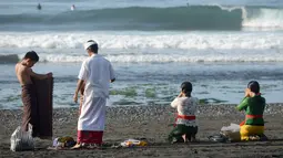 Sebuah keluarga berdoa sebelum menjalani prosesi menyucikan diri saat Hari Banyu Pinaruh di pantai Keramas, Gianyar, Bali, Minggu (12/5/2019). Banyu Pinaruh adalah tradisi Bali yang diadakan sehari setelah merayakan Hari Suci Saraswati untuk membersihkan jiwa dan raga. (SONNY TUMBELAKA/AFP)