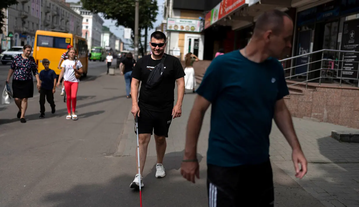 Dipandu oleh pelatih Vasyl Hoshovskyi (depan), Denys Abdulin seorang mantan tentara Ukraina yang buta akibat perang belajar menavigasi jalan-jalan Rivne. (AP Photo/Jae C. Hong)