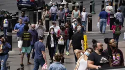 Pejalan kaki dengan masker dan tanpa masker berjalan di sepanjang Las Vegas Strip, di Las Vegas Selasa (27/4/2021). Warga Amerika Serikat (AS) yang telah menerima vaksin COVID-19 tidak lagi diwajibkan mengenakan masker saat berada di luar ruangan jika tidak ada kerumuman. (AP Photo/John Locher)