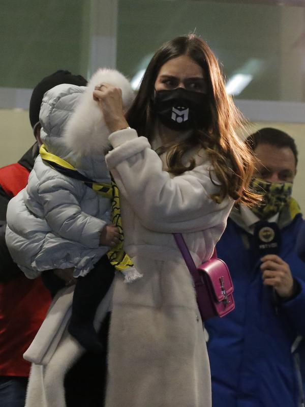 Amine Gulse, istri Mesut Ozil, menggendong putri mereka Eda, setelah tiba di Bandara Ataturk di Istanbul (18/1/2021). Fenerbahce pun kini mendapatkan Ozil dengan status bebas transfer. Ozil bakal pakai nomor punggung 67 di klub asal Istanbul tersebut. (AP Photo)
