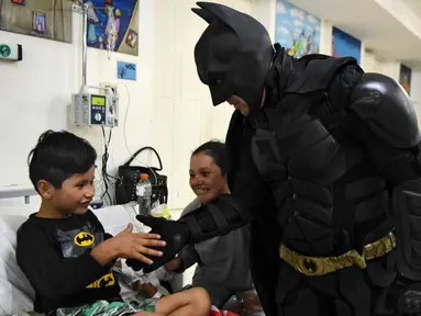 Seorang pria berkostum Batman menyalami seorang pasien anak di RS Anak 'Sor Maria Ludovica' di La Plata, Buenos Aires, Argentina, Jumat (2/6). Kehadiran Batman ini menjadi hiburan bagi anak-anak di rumah sakit tersebut. (AFP FOTO / Eitan ABRAMOVICH)