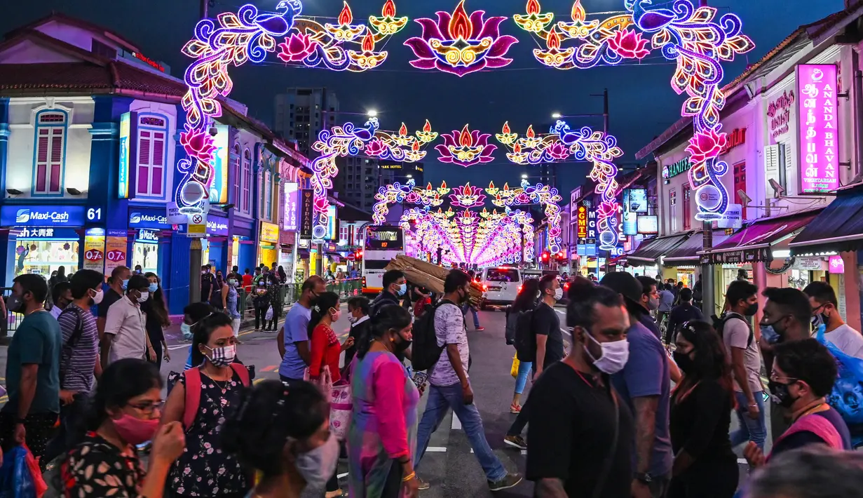 Pejalan kaki melintasi jalan yang dihiasi dekorasi meriah menjelang Diwali, festival cahaya bagi umat Hindu, di distrik Little India di Singapura pada 23 Oktober 2020. (Photo by Roslan RAHMAN / AFP)