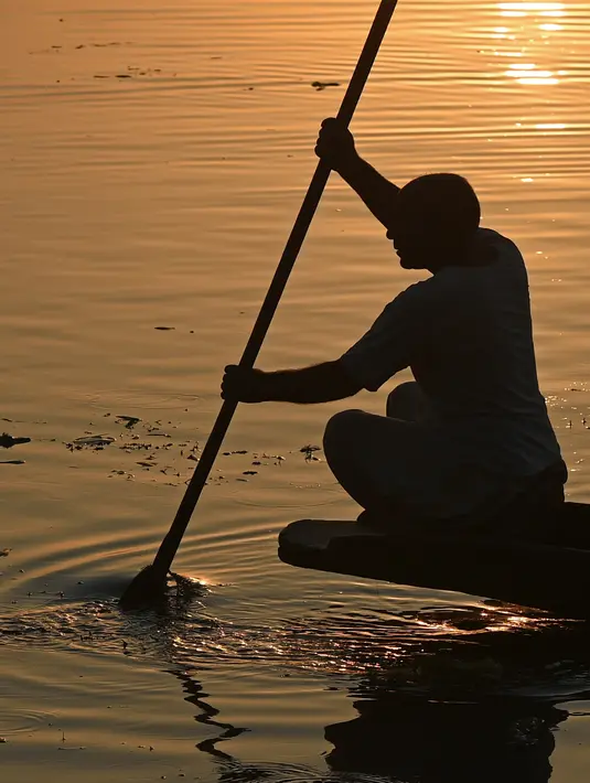 Seorang nelayan Kashmir mengayuh perahunya saat matahari terbenam di danau Dal di Srinagar, India (12/9). Danau Dal dijuluki sebagai Jewel in the Crown of Kashmir atau Srinagar Jewel. (AFP Photo/Tauseef Mustafa)