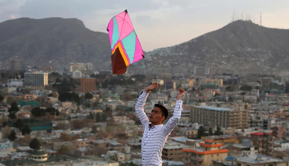 Seorang pria bermain layangan selama perayaan Nowruz di Kabul, (21/3). Meskipun serangan di Kabul menewaskan sedikitnya 29 orang, warga tetap datang di jalanan dengan pakaian berwarna-warni dan terus merayakan Nowruz. (AP Photo/Rahmat Gul)