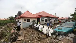 Orang-orang berusaha untuk menarik gerbang yang ditarik oleh air banjir di jalan yang terkena banjir bandang setelah hujan deras di Trademoore Estate, Lugbe, Abuja, Nigeria (13/9/2021). (AFP/Kola Sulaimon)