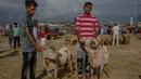 Dua orang pedagang memegang domba untuk kurban Idul Adha yang diwarnai di Srinagar, Kashmir (30/8). Hewan kurban tersebut diberi warna untuk menarik para pembeli. (AP Photo/Dar Yasin)