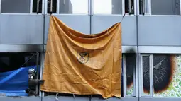 Petugas pemadam kebakaran menggunakan lembaran plastik untuk menutupi jendela sebuah gedung, tempat kebakaran terjadi di Osaka (17/12/2021). Kebakaran terjadi di lantai empat atau lima sebuah gedung berlantai delapan di kawasan perbelanjaan dan hiburan di kota Osaka. (AFP/STR/Jiji Pers)