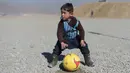 Anak laki-laki Afganistan, Murtaza Ahmadi, sedang bermain bola di Kabul, Afganistan, (1/2/2016). Lionel Messi berharap bisa bertemu dengannya setelah melihat foto Murtaza Ahmadi memakai jersey Messi dari plastik di internet. (AFP/Shah Marai)