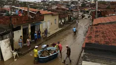 Warga membersihkan rumah mereka yang terendam banjir di Itapetinga, negara bagian Bahia, Brasil, Selasa (28/12/2021). Dua bendungan jebol pada Minggu (26/12) di timur laut Brasil, mengancam banjir yang lebih parah di wilayah yang diguyur hujan. (AP/Raphael Muller)