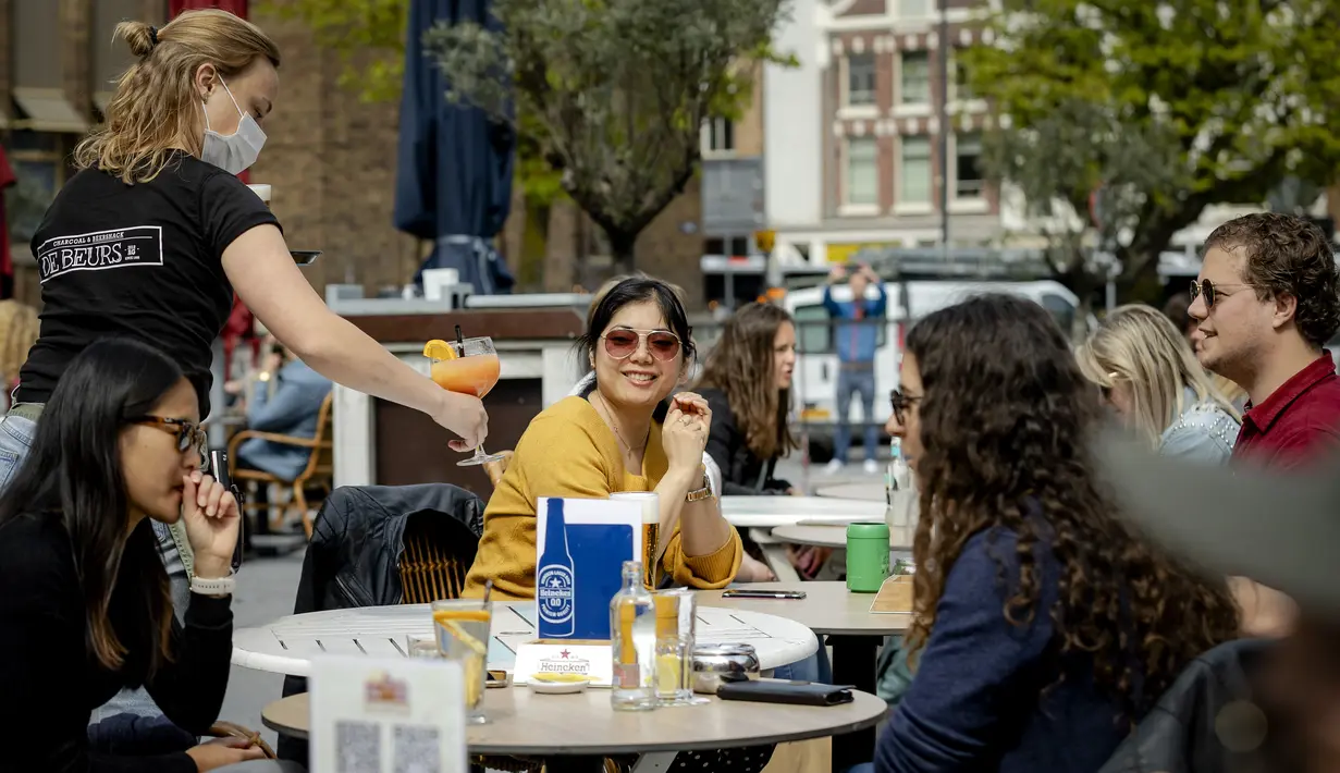 Pelanggan menikmati minuman di teras di Neude plaza di Utrecht, Belanda Barat, Rabu (28/4/2021). Pemerintah Belanda mulai melonggarkan pembatasan ketat terkait Covid-19, mengakhiri jam malam yang kontroversial dan mengizinkan kafe untuk buka di luar ruangan. (ROBIN VAN LONKHUIJSEN/ANP/AFP)