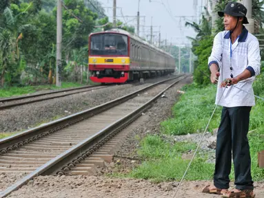 Akibat tidak adanya penjaga perlintasan kereta api, Muhamad Ali warga Pondok Cina berinisiatif untuk mejaga pos jaga perlintasan kereta api yang dibuat secara swadaya, Depok, Minggu (13/12/2015). (Liputan6.com/Yoppy Renato)