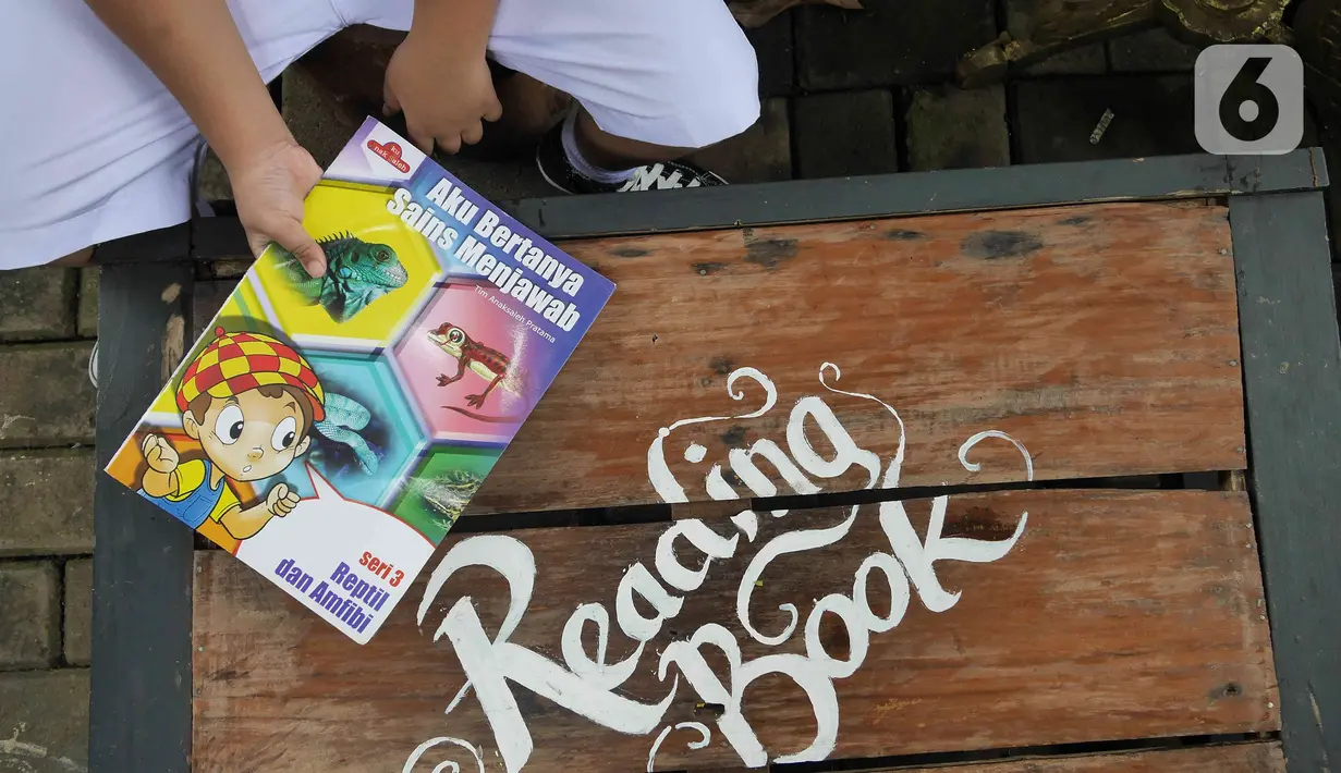 Seorang anak membaca buku di pustaka mini Bale Buku, Kramat Jati, Jakarta Timur, Kamis (20/01/2022). Bale buku yang diresmikan pada Sabtu (15/1) dibangun dari barang-barang bekas oleh komunitas Baca Bale Buku. (Liputan6.com/Herman Zakharia)