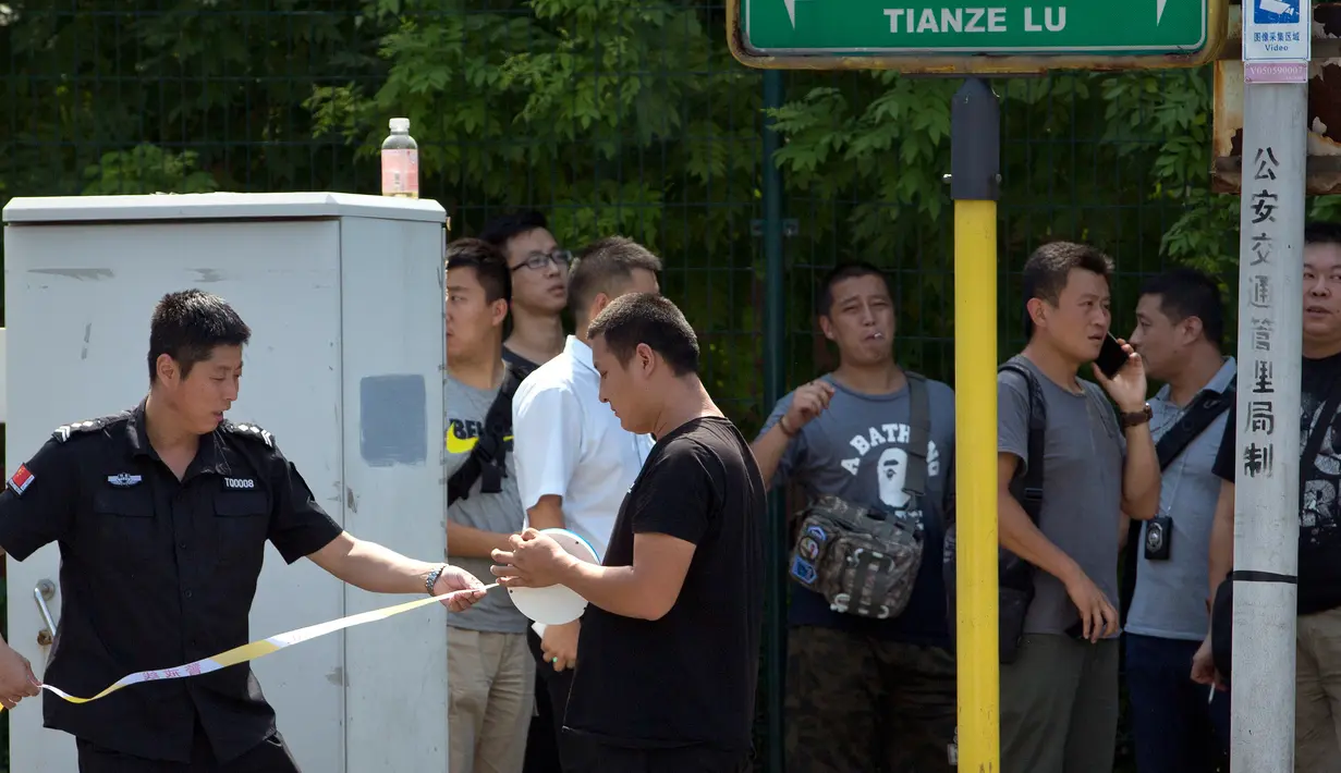 Personel keamanan China memasang garis polisi dekat lokasi ledakan yang dilaporkan terjadi di kedutaan besar Amerika Serikat di Beijing, Kamis (26/7). Sejumlah orang berseragam militer terlihat berjaga di sekitar lokasi ledakan. (AP/Mark Schiefelbein)