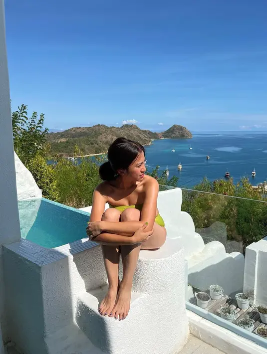Tyna Dwi Jayanti berpose sedang berjemur di bawah sinar matahari. Dia tampil seksi mengenakan bikini two piece model bandeau warna hijau neon. (Instagram/tynadwijayanti)