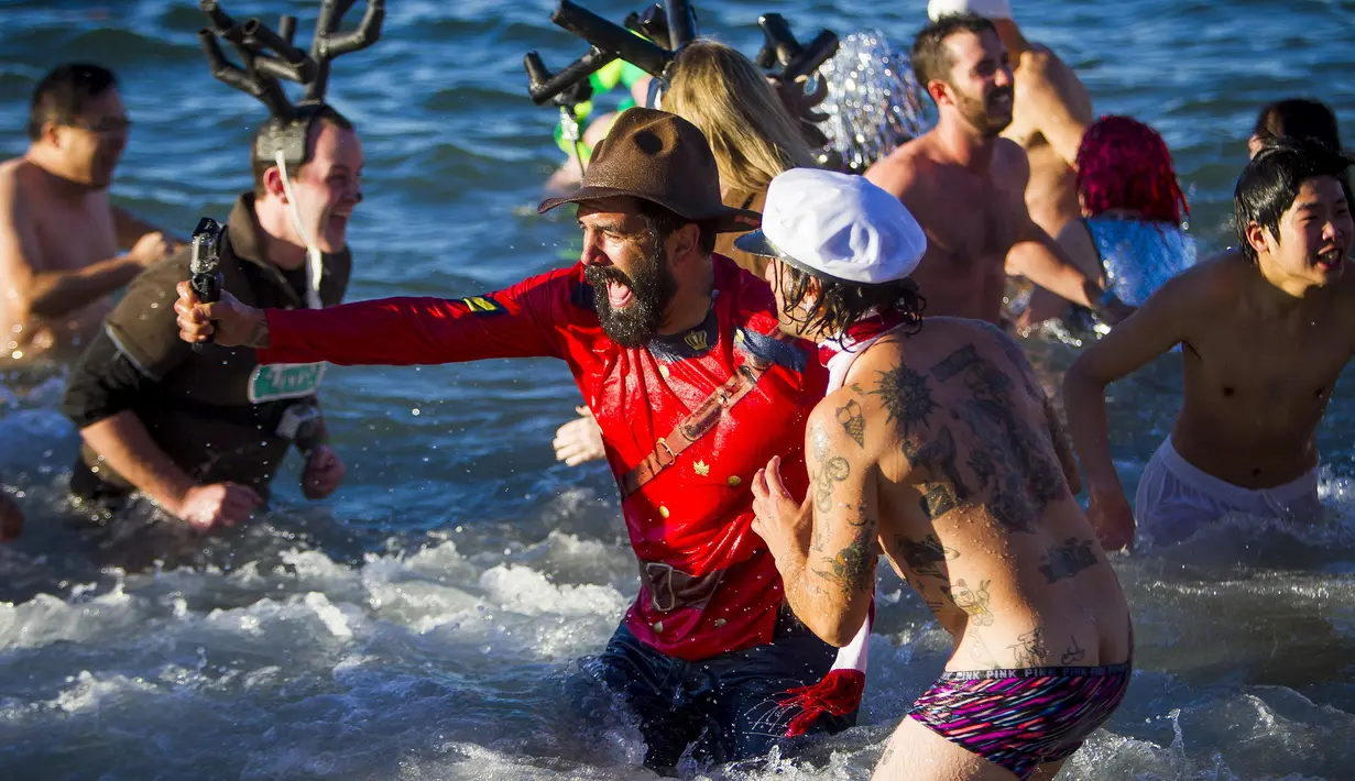 Dua orang peserta berpose bersama saat ambil bagian dari acara tahunan Polar Bear Swim di Vancouver, Kanada (2/1/2016). Meski suhu di pantai tersebut mencapai 3 derajat celcius, mereka tetap antusias. (REUTERS / Ben Nelms)