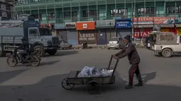 Seorang pria Kashmir mendorong kereta tangannya saat dia berjalan melewati area pasar tertutup selama penguncian akhir pekan di Srinagar, Kashmir yang dikuasai India, Sabtu (15/1/2022). Pihak berwenang di bagian Kashmir India mengumumkan pembatasan penuh selama akhir pekan. (AP Photo/Dar Yasin)