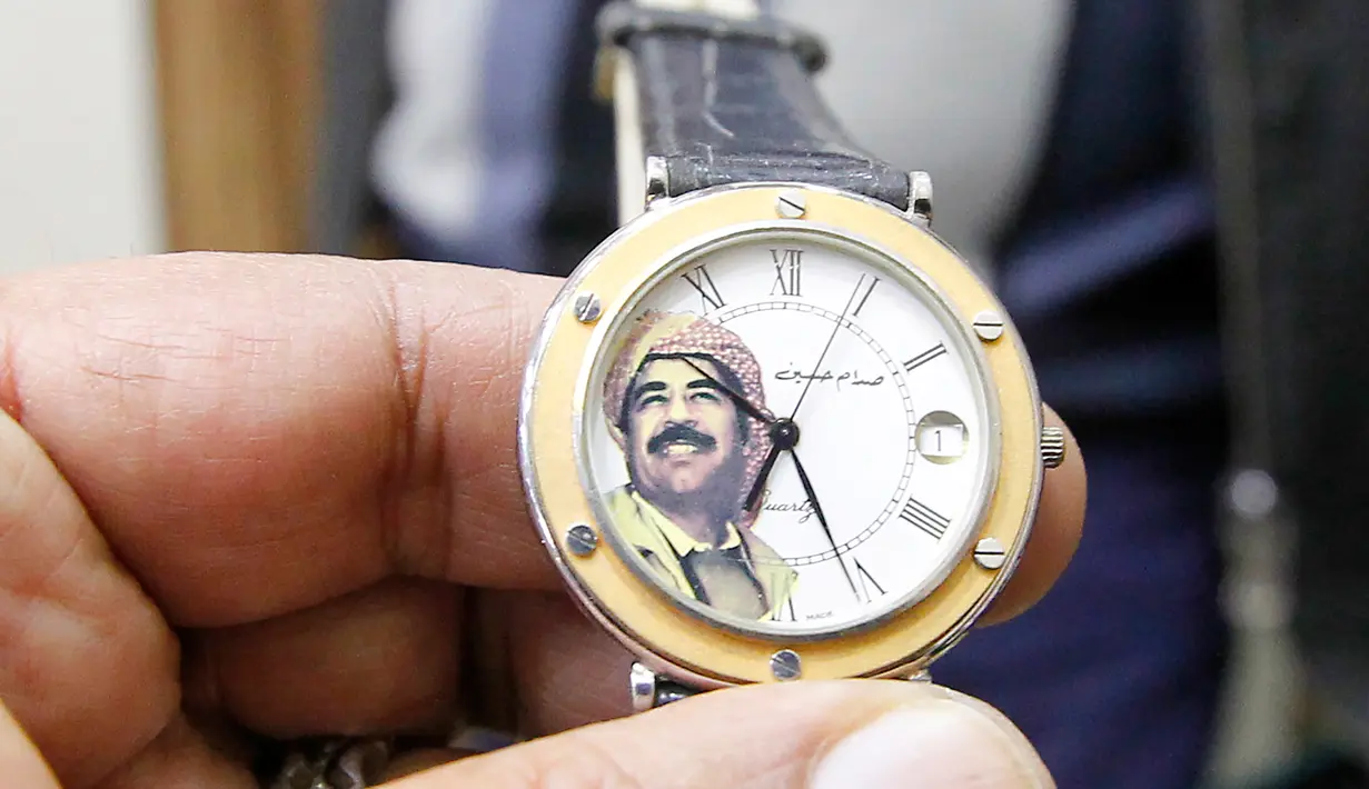 Seorang penjual menunjukan jam tangan yang bergambar mantan Presiden Irak, Saddam Hussein di Baghdad, Irak (28/12). Pada 5 November 2006 Hakim Ketua Rauf Rasheed Abdel Rahman menjatuhkan hukuman mati kepada Saddam Hussein. (AFP/Sabah Arar)