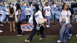 Penyanyi Billie Eilish (tengah) berjalan di lapangan sebelum pertandingan bisbol antara Los Angeles Dodgers dan San Francisco Giants di Los Angeles, Amerika Serikat, 21 Juli 2022. Billie Eilish mengenakan kemeja Dodgers ditemani saudaranya Finneas dan sejumlah teman. (AP Photo/Marcio Jose Sanchez)