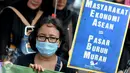 Seorang aktivis membawa tulisan saat melakukan aksi demo memperingati Hari Ibu di depan Istana Negara, Jakarta (22/12). Hal ini dilakukan dalam menyambut berlakunya Masyarakat Ekonomi ASEAN di Indonesia. (Liputan6.com/Gempur M Surya)
