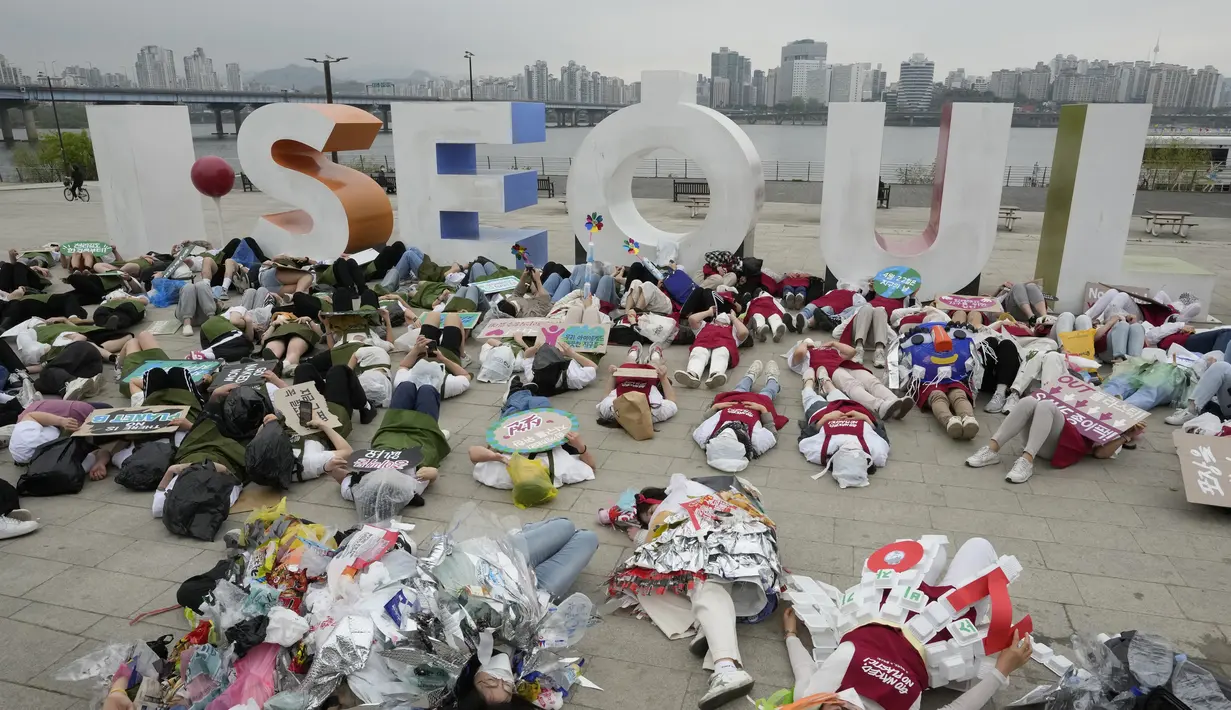 <p>Aktivis lingkungan mengenakan pakaian yang terbuat dari sampah plastik berbaring di tanah selama kampanye untuk memperingati Hari Bumi melawan perubahan iklim di Seoul, Korea Selatan, Jumat (22/4/2022). (AP Photo/Ahn Young-joon)</p>