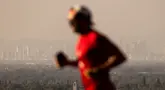 Seorang pelari melintas di depan kabut asap dari berbagai kebakaran hutan di cakrawala pusat kota Los Angeles, Rabu, 11 September 2024. (AP Photo/Etienne Laurent)