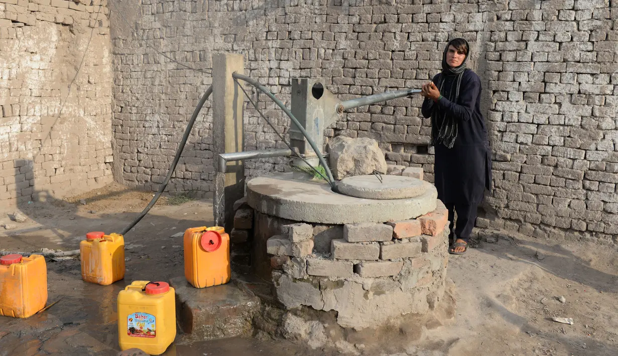 Perempuan Afghanistan, Sitara Wafadar yang menyamar sebagai laki-laki mengambil air di rumahnya, Provinsi Nangarhar, 20 Maret 2018. Setiap pagi, Sitara memakai kemeja, celana panjang dan sandal yang biasa dikenakan pria Afganistan (NOORULLAH SHIRZADA/AFP)