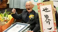 Chitetsu Watanabe Jepang, berusia 112 tahun, berpose di sebelah pembacaan kaligrafi 'Nomor Satu Dunia' Jepang setelah ia dianugerahi sebagai pria tertua yang hidup di dunia. (Liputan6/AFP)