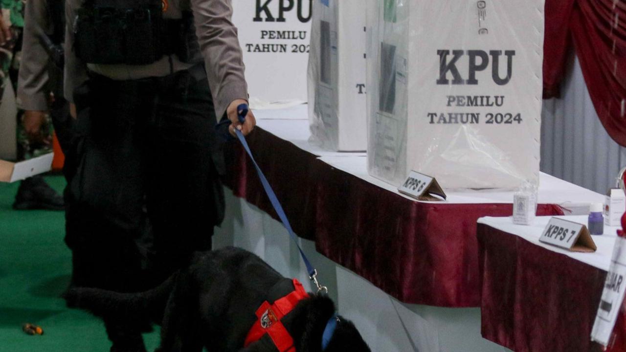 Petugas kepolisan mengerahkan K9 di TPS 033, Bojong Koneng, Kabupaten Bogor, Jawa Barat, Rabu (14/2/2024). Pengerahan anjing pelacak K9 tersebut dilakukan untuk keamanan dan kelancaran momen pencoblosan di tempat itu. Foto: Liputan6.com / Herman Zakharia