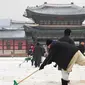 Pekerja membersihkan salju di istana Gyeongbokgung setelah salju turun Seoul, Korea Selatan (15/2). Istana ini hancur pada saat invasi Jepang ke Korea tahun 1592-1598dan dibangun lagi selama tahun 1860-an. (AFP Photo/Jung Yeon-je)