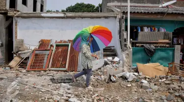 Warga melintas di sisa gusuran bangunan di Kali Sekretaris, Kampung Rawa, Jakarta, Selasa (17/11). Warga menyesalkan sikap Gubernur Ahok yang pernah menjanjikan tidak akan ada penggusuran sebelum mendapat kunci rumah susun. (Liputan6.com/Gempur M Surya)