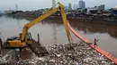 Petugas kebersihkan dibantu alat berat membersihkan sampah di Sungai Kanal Banjir Barat, Jakarta, Senin (14/11). Hujan yang terjadi di hulu Banjir Kanal Barat mengakibatkan meningkatnya debit air yang disertai sampah. (Liputan6.com/Johan Tallo)