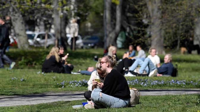 Orang-orang menikmati makan siang dengan menjaga jarak di Taman Humlegarden, Stockholm, Rabu (22/4/2020). Swedia belum memberlakukan lockdown, namum pemerintah memberikan tanggung jawab yang besar kepada penduduknya untuk membantu mengurangi penyebaran virus corona. (Janerik Henriksson / TT via AP)