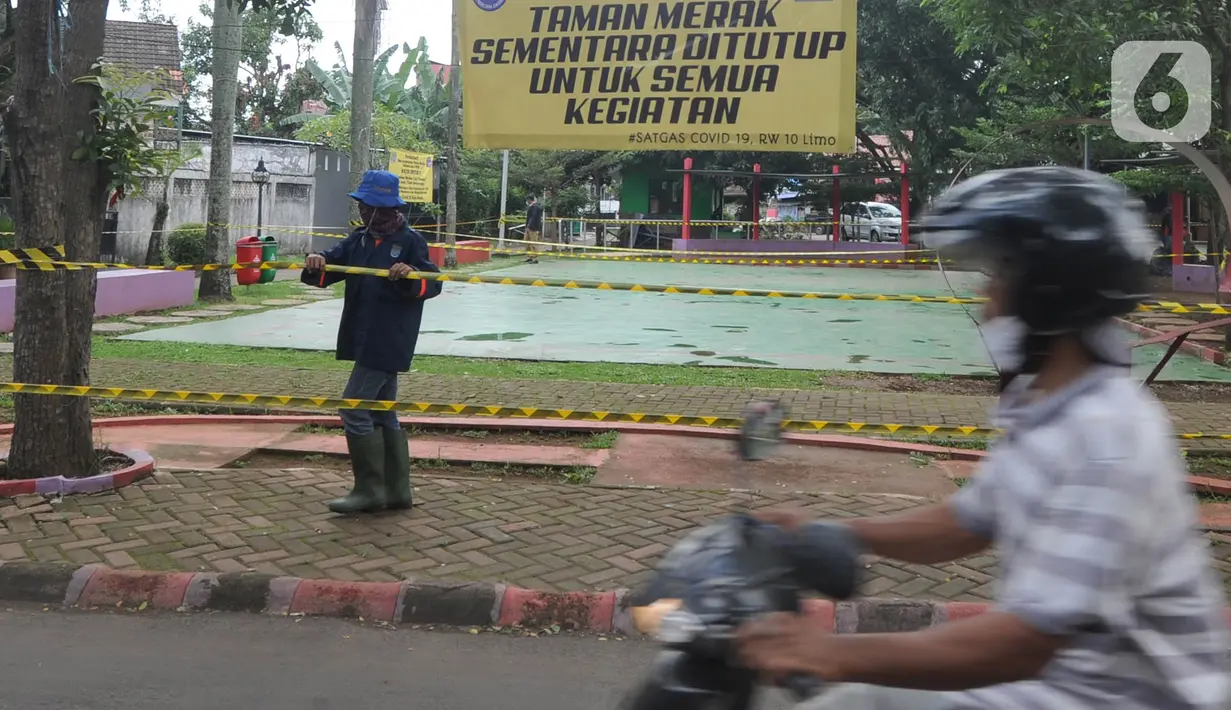 Pengendara melintas saat petugas memasang garis larangan melintas umum di Taman Merak, Limo, Depok, Senin (25/1/2021). Penutupan taman tersebut dilakukan dalam rangka Pemberlakuan Pembatasan Kegiatan Masyarakat (PPKM) untuk mengendalikan pandemi virus corona (Covid-19). (merdeka.com/Arie Basuki)