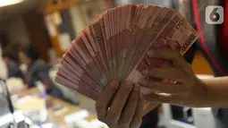 Teller menunjukkan mata uang rupiah di Jakarta, Selasa (15/10/219). Rupiah di pasar spot ditutup di level Rp 14.166 per dolar AS. (Liputan6.com/Angga Yuniar)